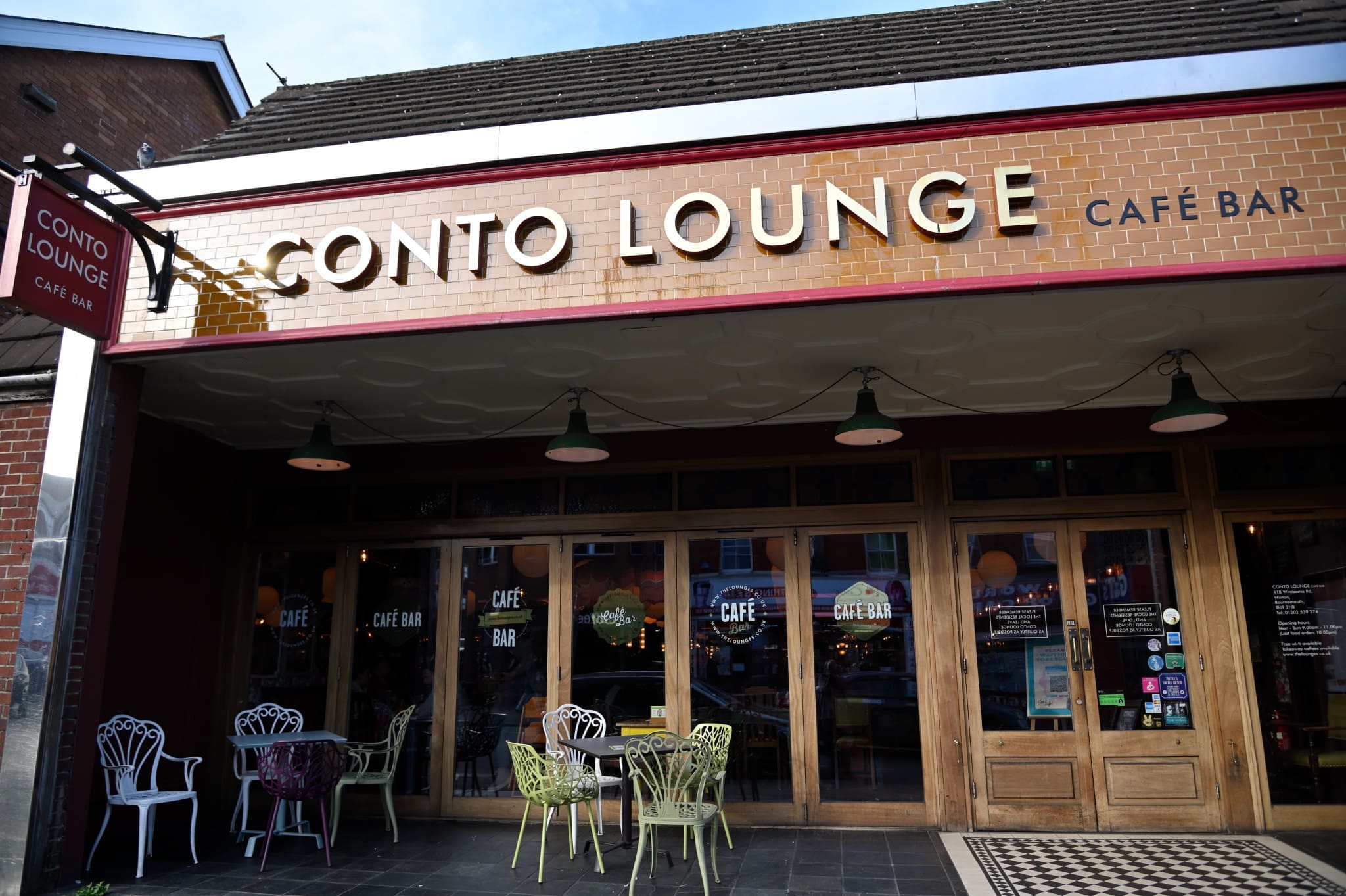 The exterior of Conto Lounge café bar features large windows, outdoor seating with colorful chairs and tables, and a prominent Conto sign displaying the café's name.